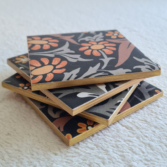 Stacked Set of four handmade William Morris Blackthorn ceramic coasters in the Charcoal Grey colourway, with metallic edging.