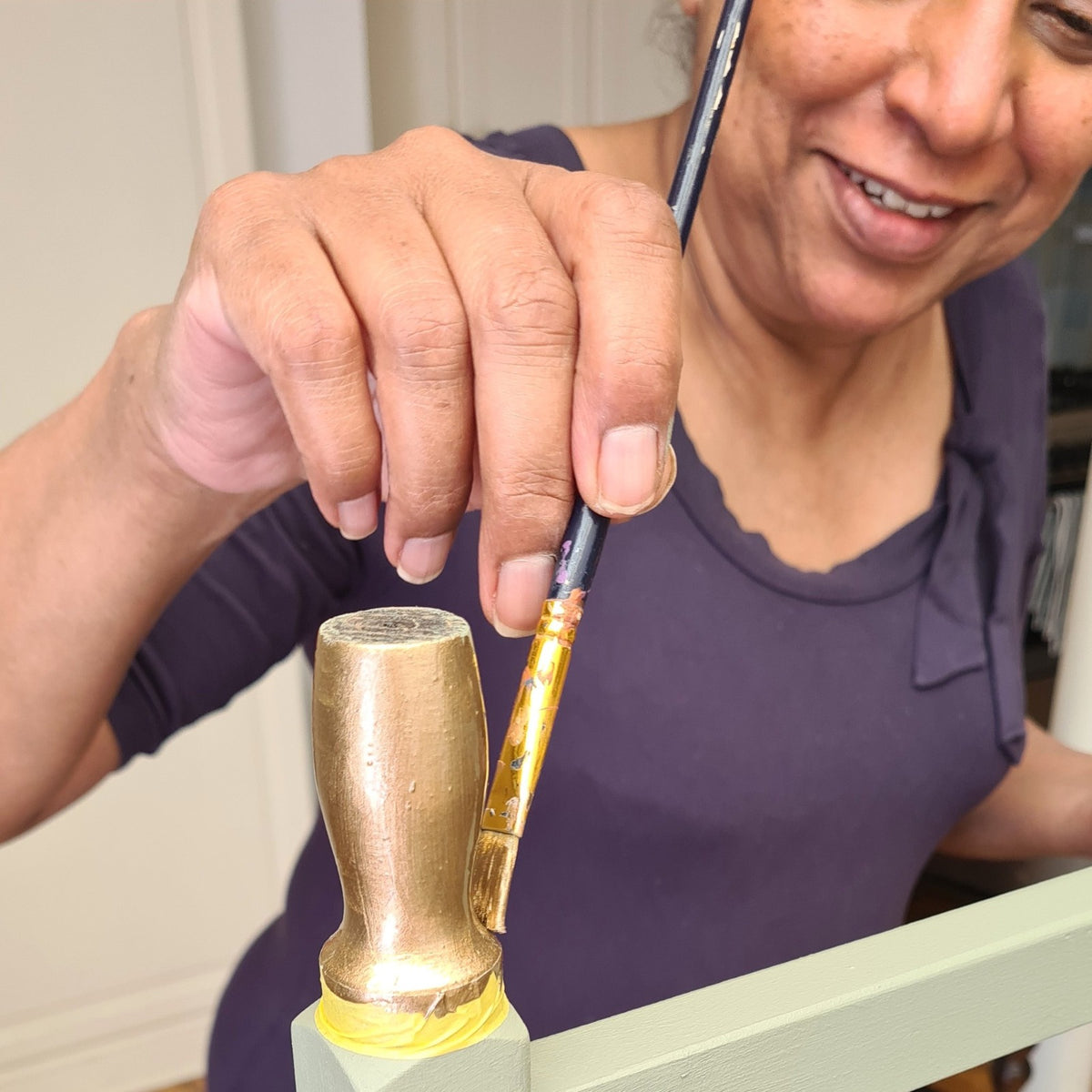 Learning to add metallic details to furniture during a 1-to-1 furniture painting workshop