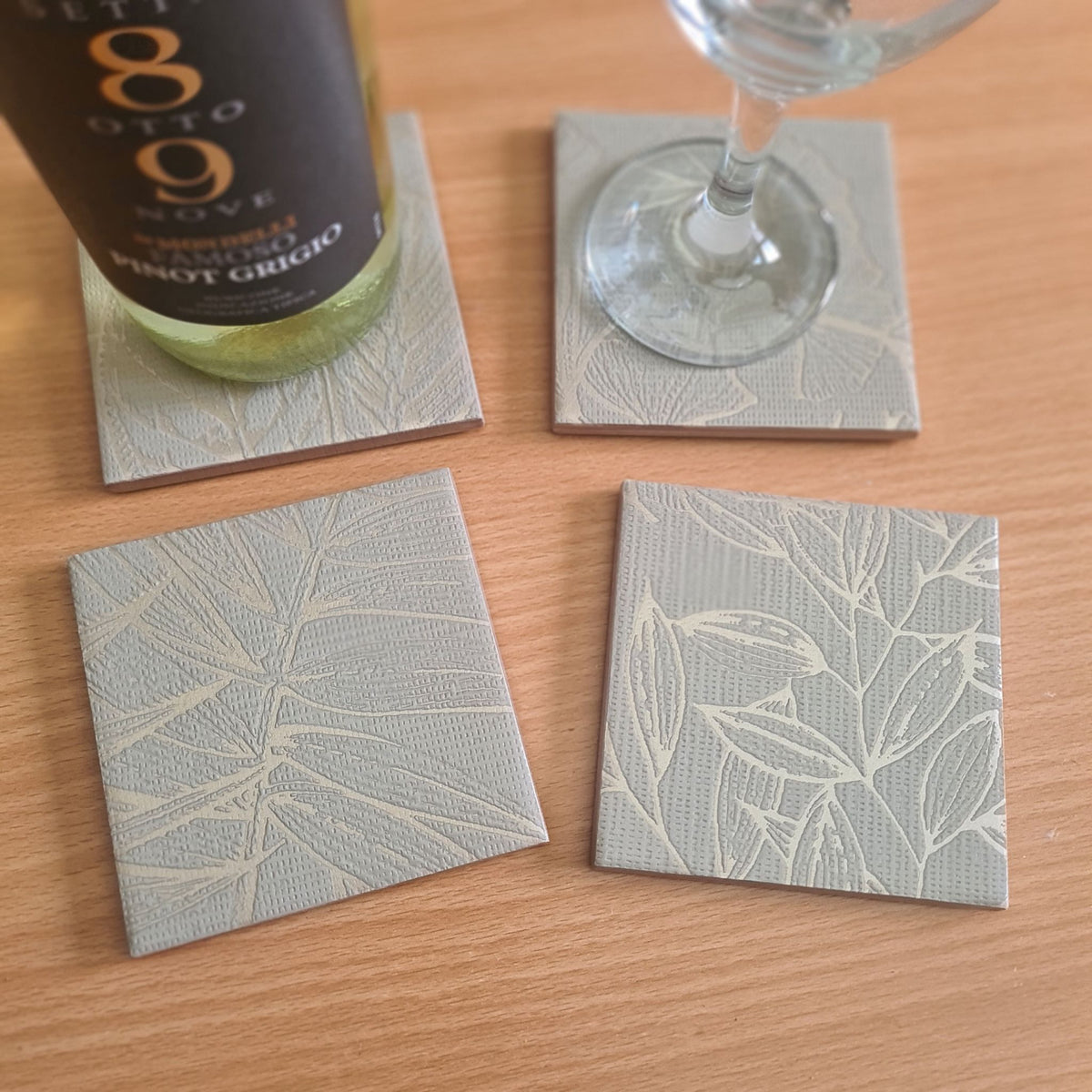 Handmade sage green ceramic coasters featuring delicate ginkgo leaves with metallic Champagne highlights.