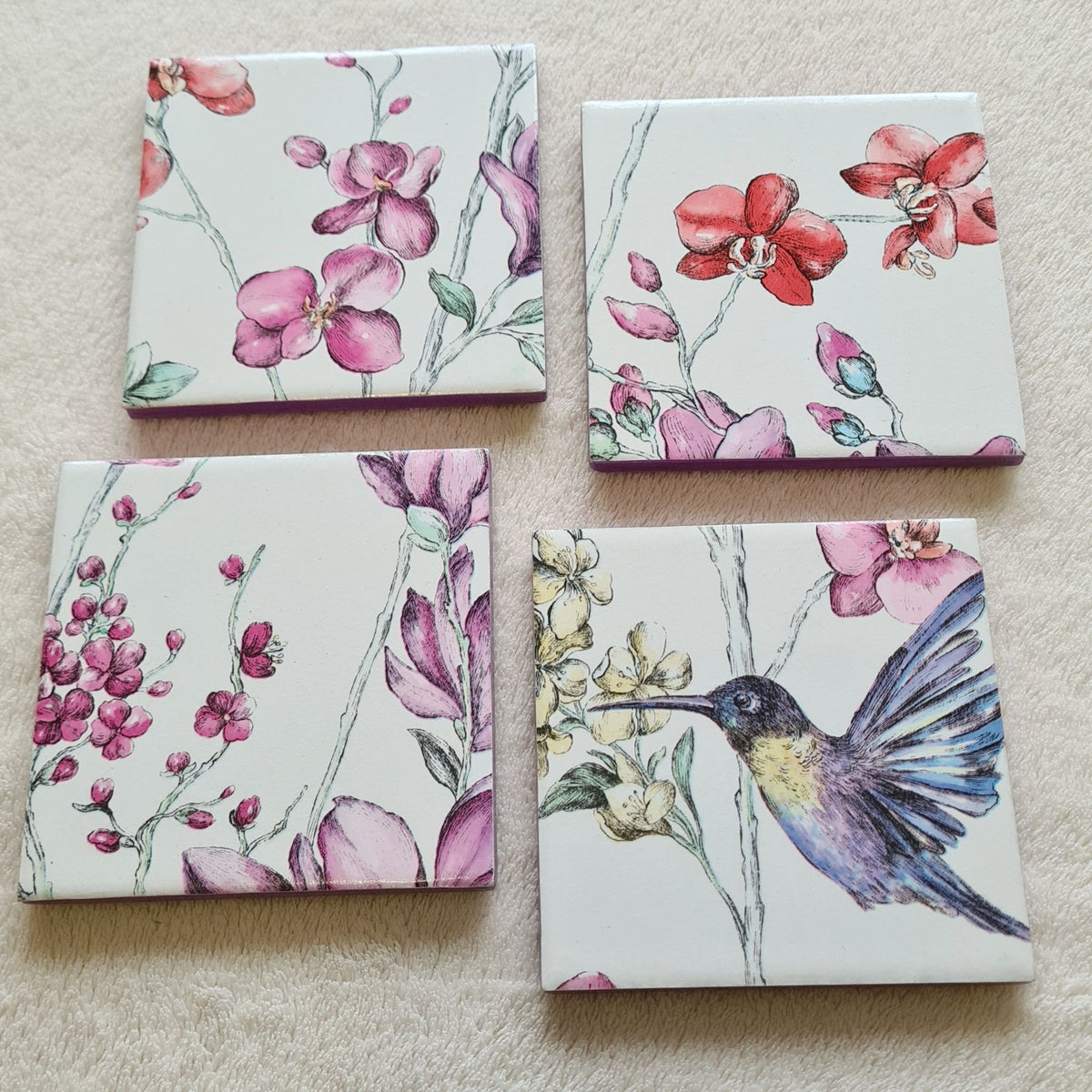 Set of four handmade Hummingbird Floral ceramic coasters with metallic violet edging.