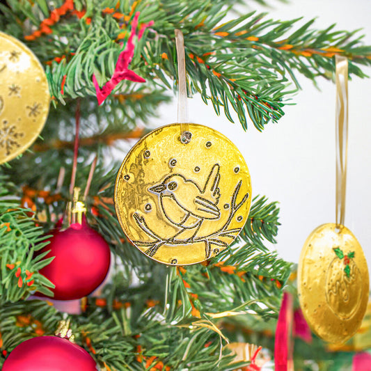 Handmade gold embossed Christmas bauble decorations hanging on a Christmas tree.