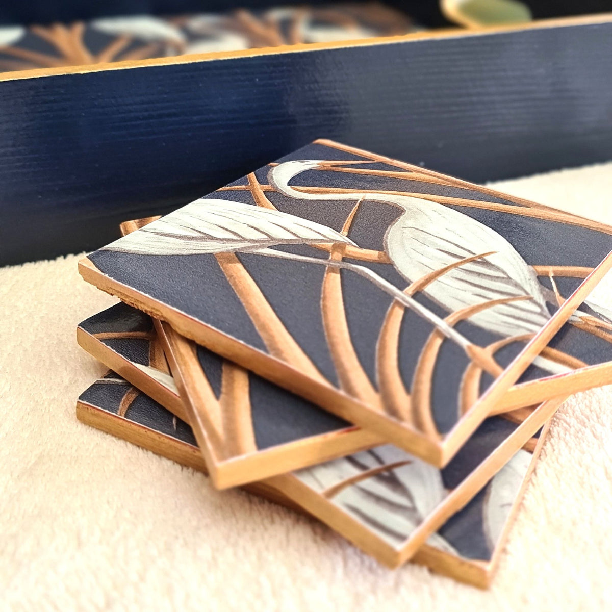 Navy wooden serving tray decorated with Angel Strawbridge Nouveau Heron design and metallic bronze edging, with stacked matching coasters, available separately.