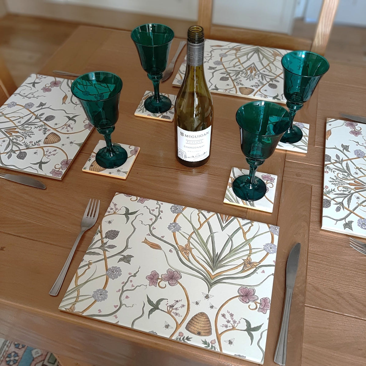 A styled dining table setting featuring rectangular ceramic placemats and coasters in Chateau Potagerie design, created from wallpaper by The Furniture Bureau.