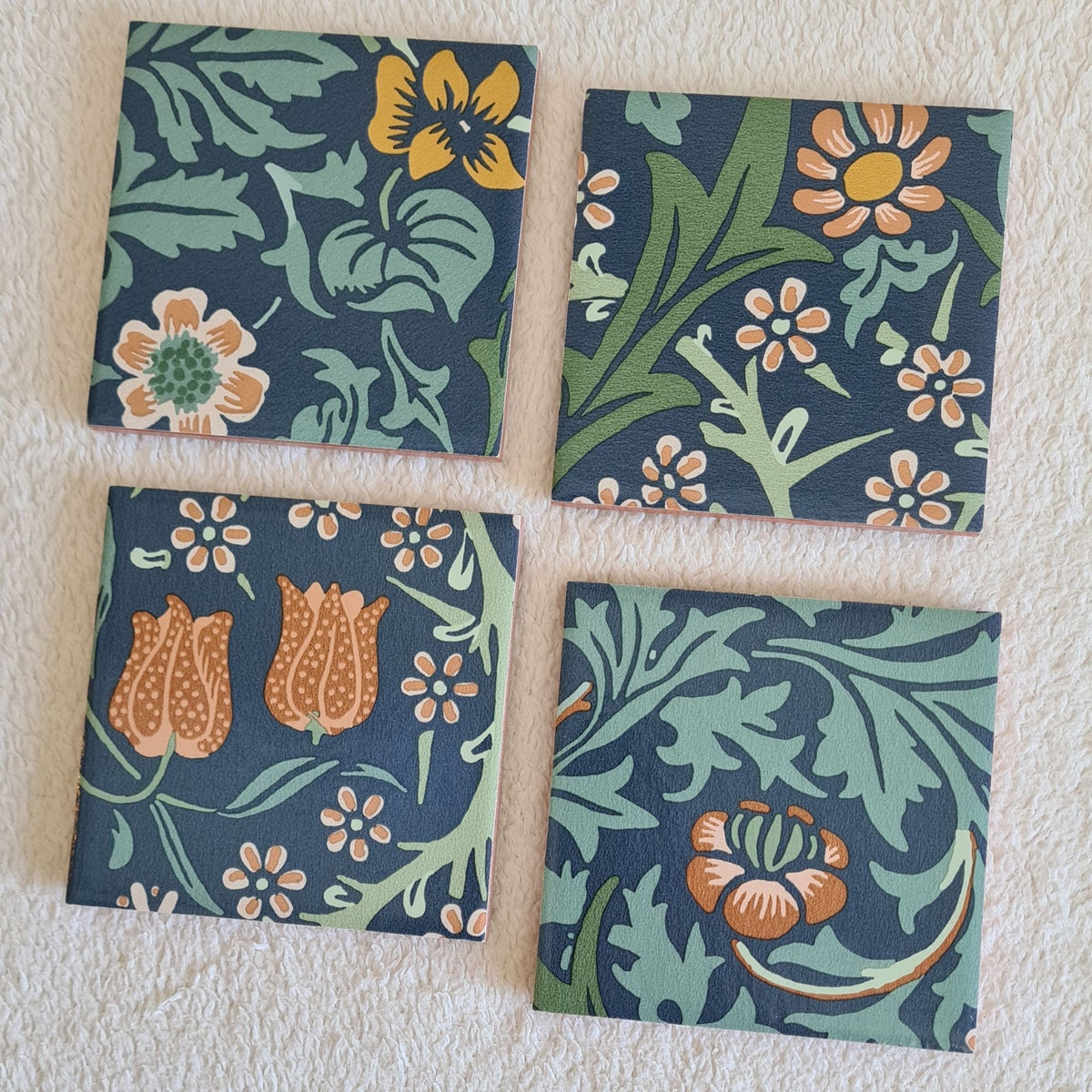 Handmade Blackthorn ceramic coasters in Slate Blue showing flowers, leaves and twisting botanical forms.