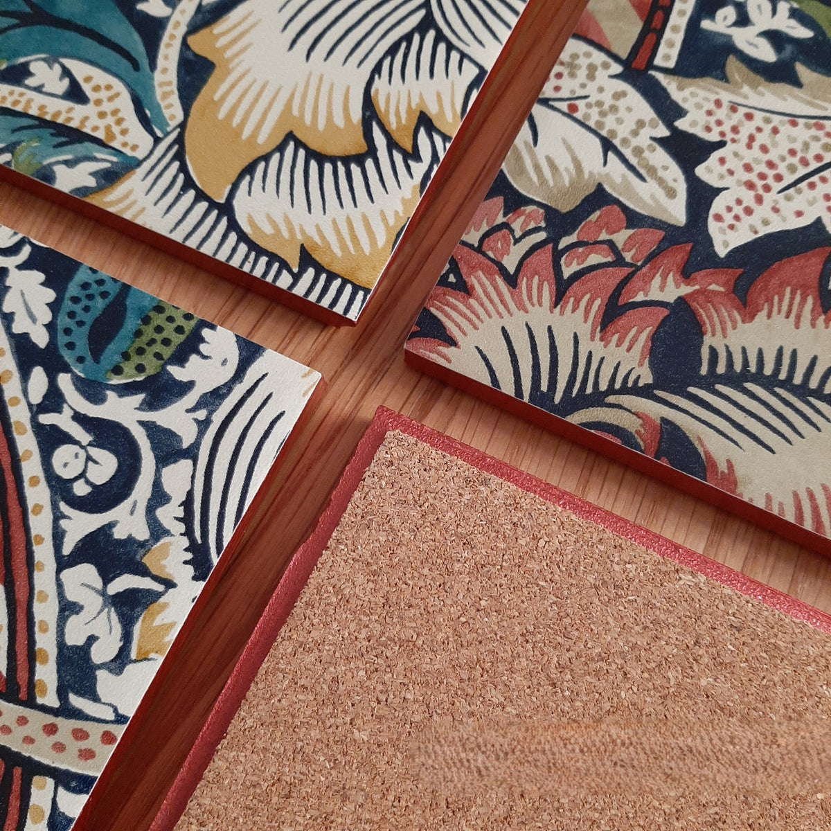 Cork backing on a handmade William Morris Wandle ceramic coaster to help protect furniture, showing rusty red metallic edging.